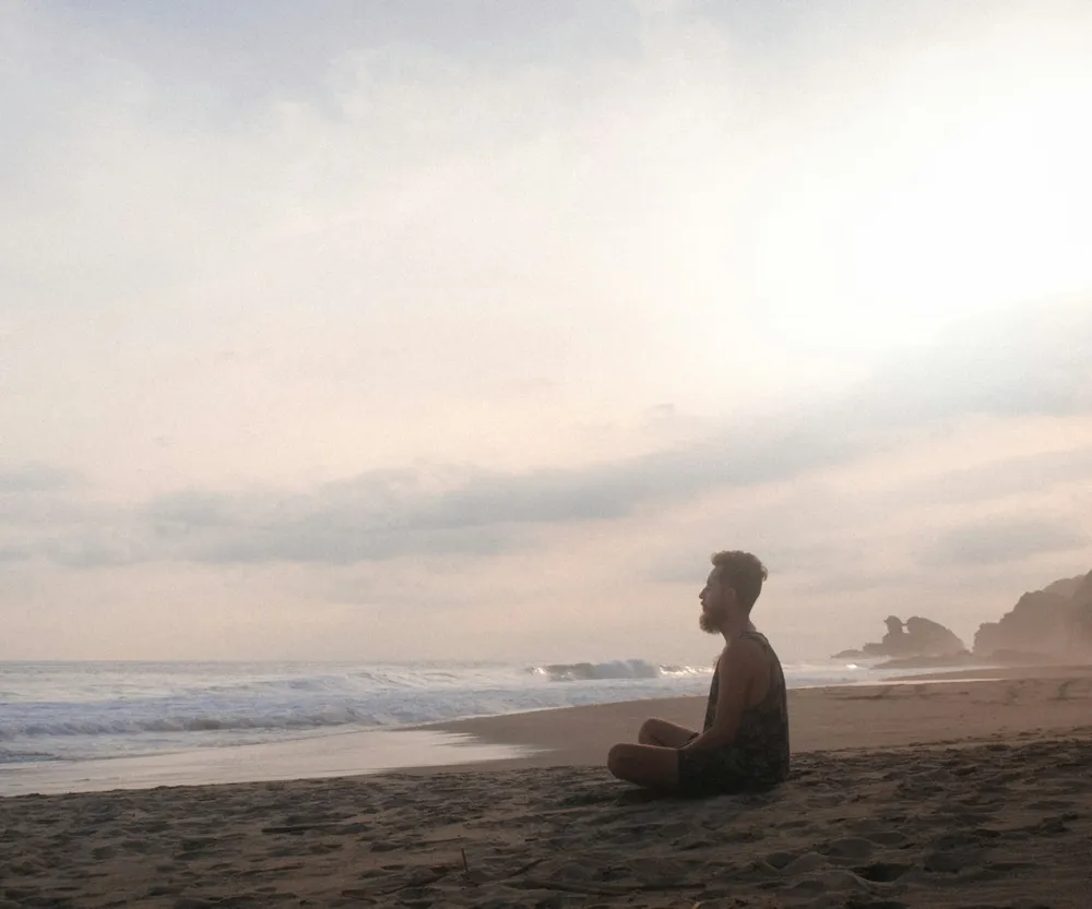 A person meditating on a quiet beach in soft morning light